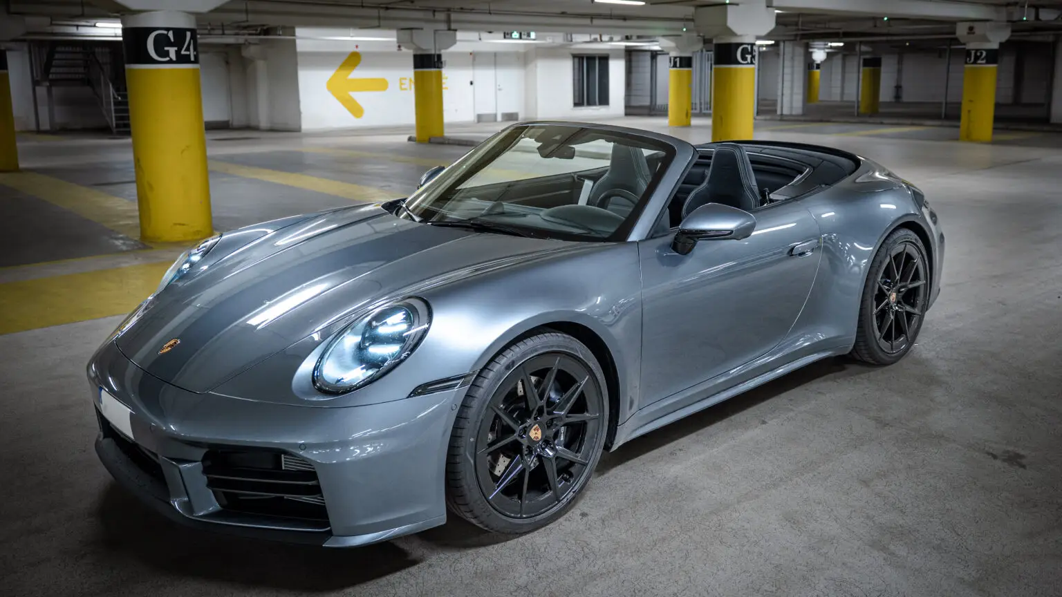 a silver convertible sports car parked in a parking lot